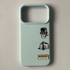 Pinkgul.no light blue phone case decorated with three small metal stickers featuring a skull, car, and caution sign.