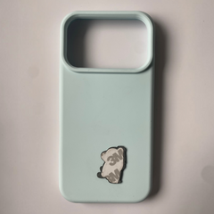 Pinkgul.no decorative metal sticker applied to a light blue phone case, showing the adhesive backing