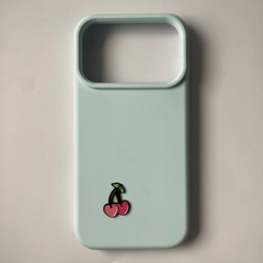 Pinkgul.no light blue phone case with a small, decorative raised metal cherry sticker attached to the back.