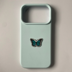 Pinkgul.no decorative metal butterfly sticker in teal and black attached to a light blue smartphone case