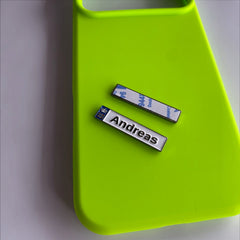 Pinkgul.no Andreas decorative metal sticker with a white finish and raised design, placed on a neon green phone case.
