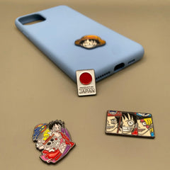 Pinkgul.no decorative metal stickers featuring One Piece anime characters applied to a light blue phone case
