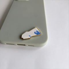 Pinkgul.no decorative metal sticker shaped like a bunad on a light green phone case