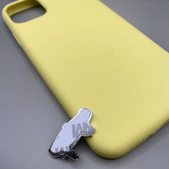 Pinkgul.no decorative metal sticker with adhesive backing placed next to a yellow smartphone case