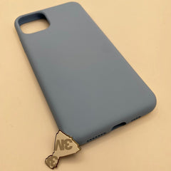 Pinkgul.no decorative metal sticker with adhesive backing placed next to a matte blue smartphone case
