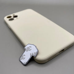 Pinkgul.no decorative metal sticker with adhesive backing placed next to a cream-colored smartphone case