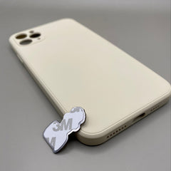 Pinkgul.no decorative metal sticker with 3M adhesive backing placed next to a beige smartphone case