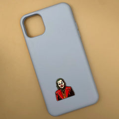Pinkgul.no decorative metal Joker sticker applied to a light blue smartphone case on a beige background