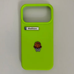 Pinkgul.no lime green phone case with a personalized Mathias metal sticker and a basketball hoop emblem.