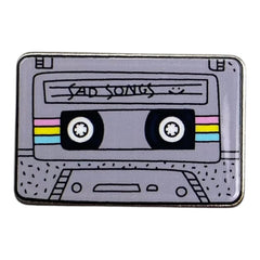 Pinkgul.no decorative metal sticker featuring a grey retro cassette tape design with Sad Songs text and colorful stripes