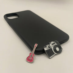 Pinkgul.no decorative metal stickers featuring a pink guitar and a camera design on a black smartphone case.
