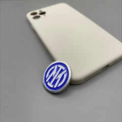 Pinkgul.no decorative metal sticker with blue and white Inter Milan logo design placed next to a beige smartphone