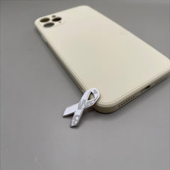 Pinkgul.no decorative metal ribbon sticker with a raised design, applied to a beige smartphone case.