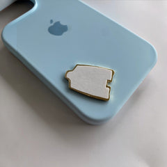 Pinkgul.no decorative metal sticker with adhesive backing placed on a light blue phone case