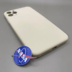 Pinkgul.no decorative round metal NASA logo sticker with a raised design placed next to a beige smartphone case.