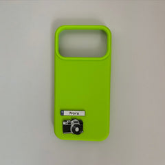 Pinkgul.no Nora decorative metal sticker featuring a camera icon on a bright lime green phone case