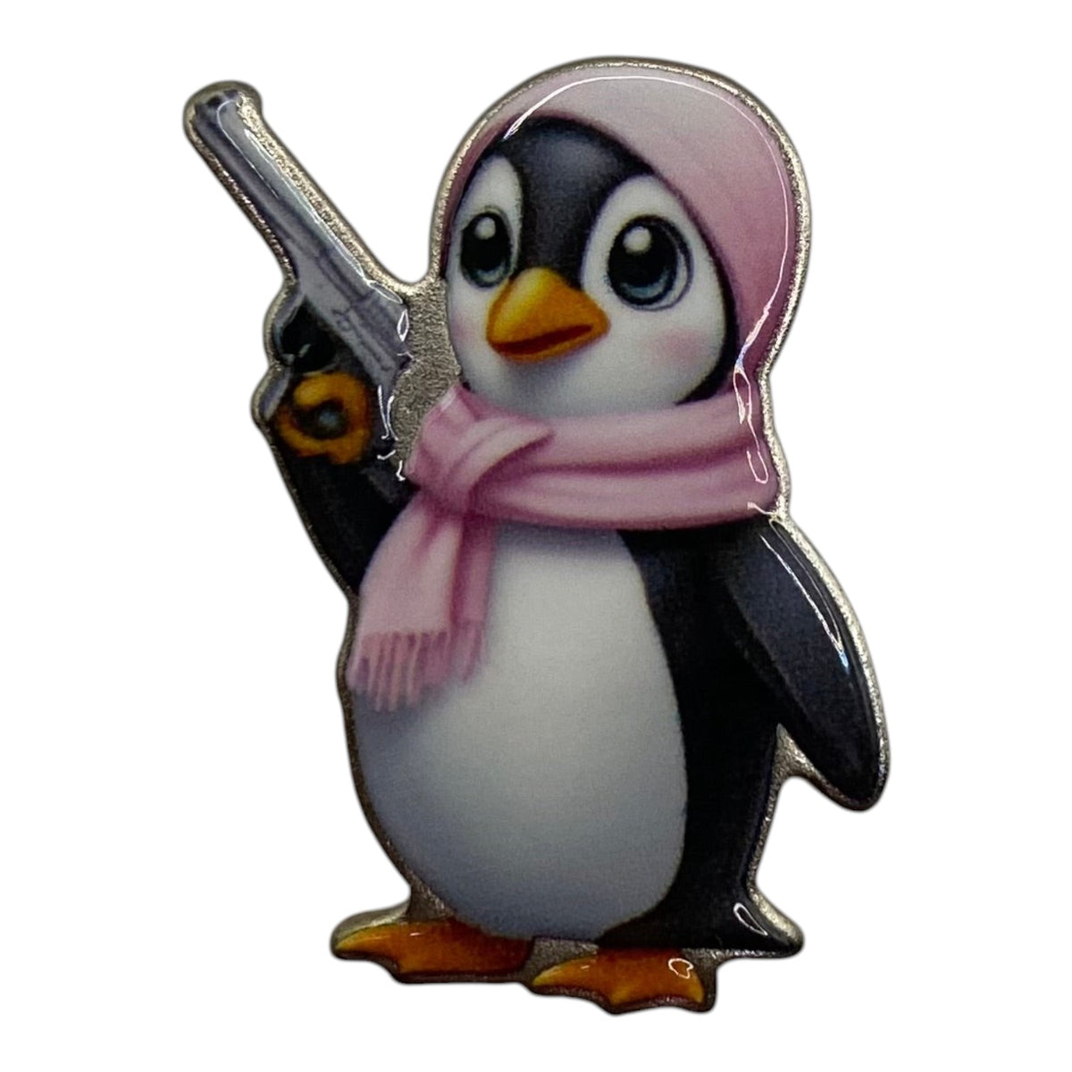 Pinkgul.no decorative metal sticker featuring a cute penguin wearing a pink hat and scarf holding a small toy gun.