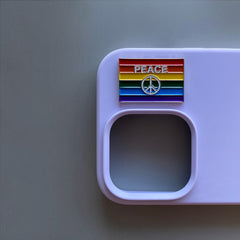 Pinkgul.no decorative metal sticker with a rainbow pride flag and peace symbol on a light purple phone case