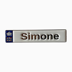 Pinkgul.no Simone decorative metal sticker with a white surface, raised lettering, and a small crown emblem.