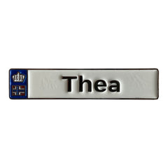 Pinkgul.no Thea decorative metal sticker with a white finish, raised lettering, and a small crown emblem.