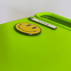Pinkgul.no Tuva decorative metal smiley face sticker applied to a bright lime green surface